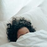 unrecognizable person sleeping under blanket